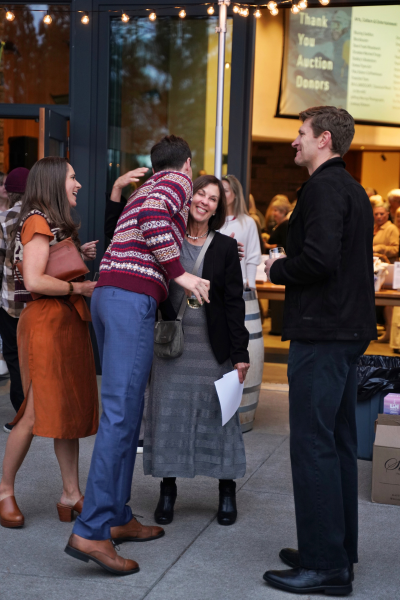 four people greet each other under string lights 